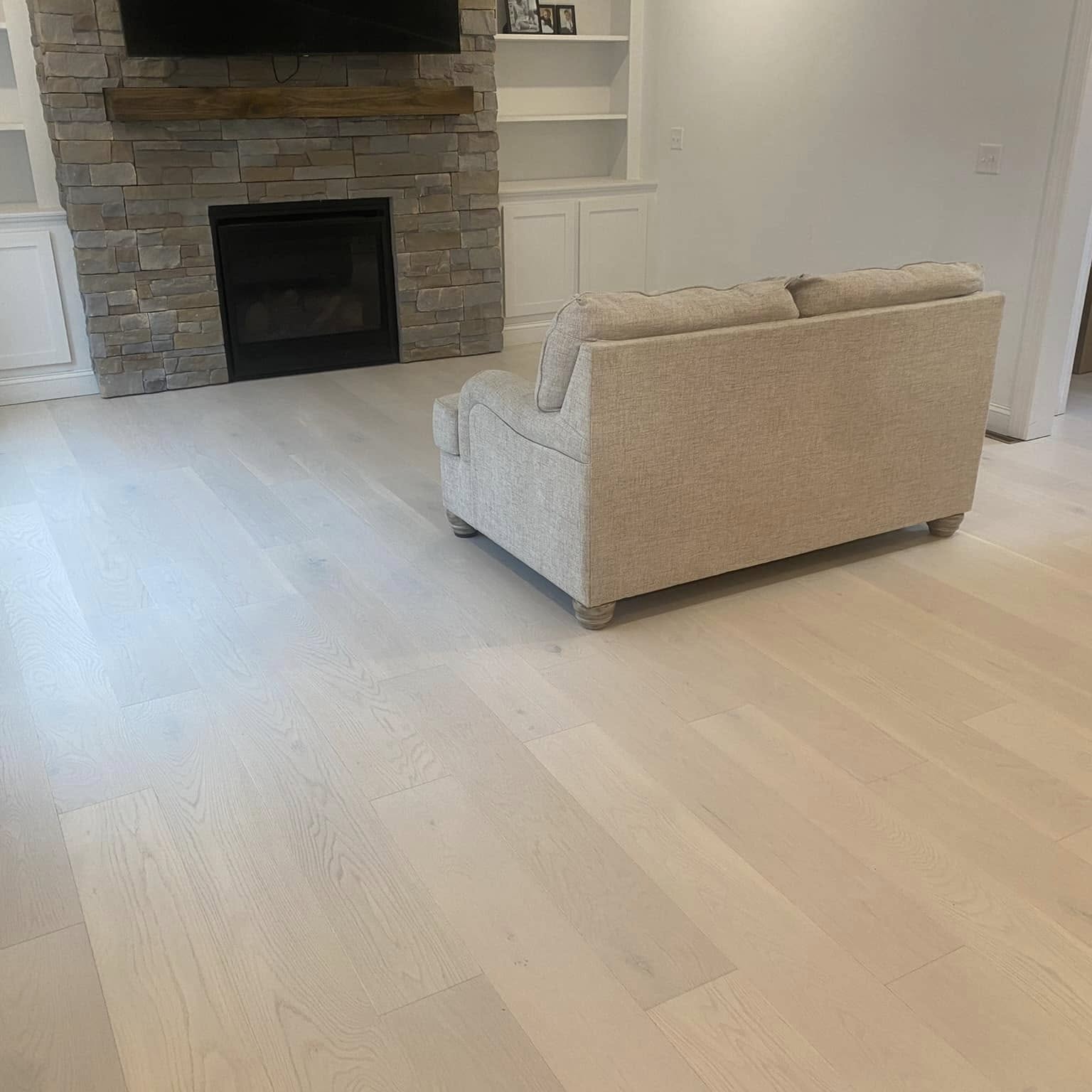 White oak flooring installed by Upstate Wood Flooring in a living room with a stone fireplace